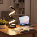 Helix Glow Table Lamp in spiral shape beside a small plant on a wooden side table